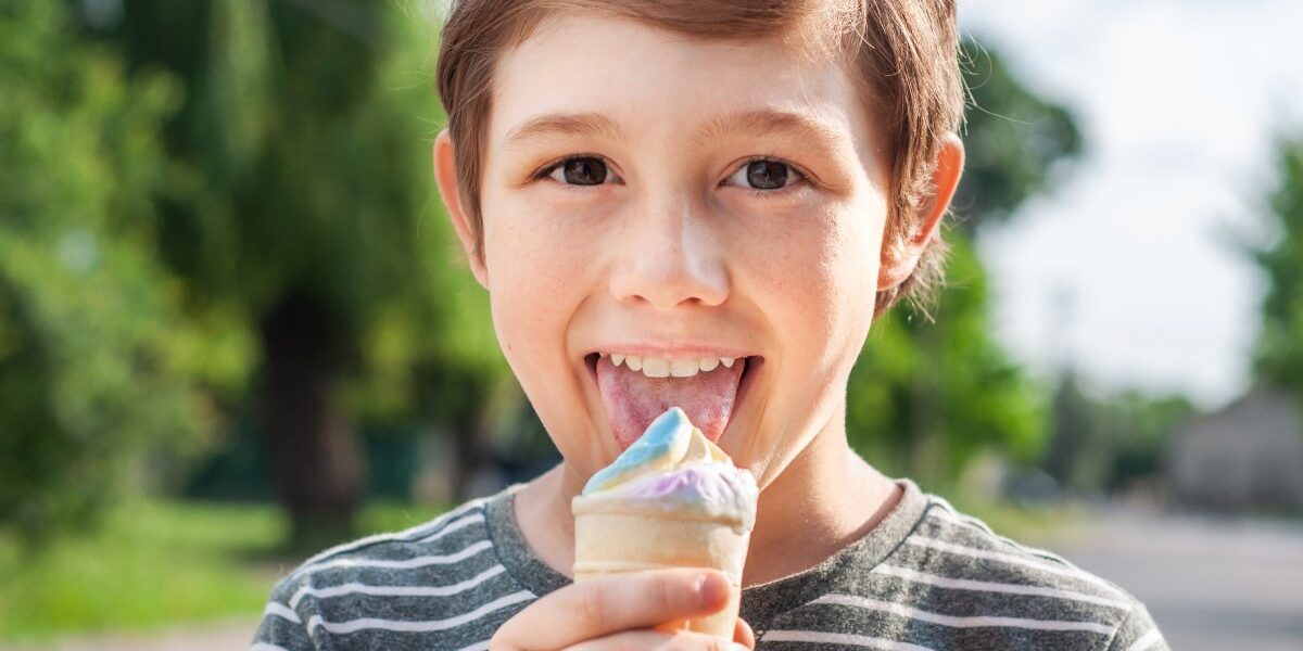 bambino con la lingua bianca mentre mangia il gelato