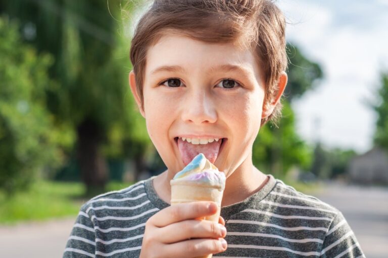 bambino con la lingua bianca mentre mangia il gelato