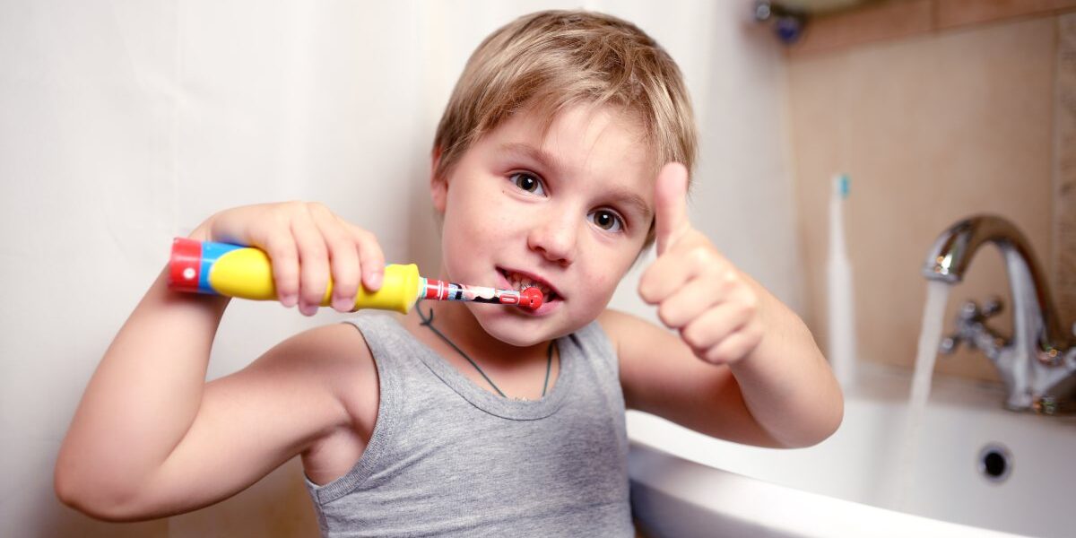 bambino che utilizza il suo spazzolino elettrico per lavare i denti